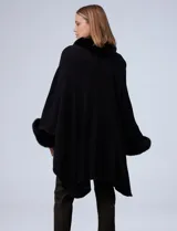 Ruana o poncho negro de tejido suave, con cuello y puños adornados con apliques de piel sintética (faux fur).