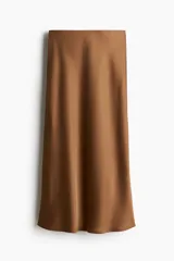 Pollera midi color marrón con leve brillo y caída suave. Modelo de tiro alto con elástico oculto en la cintura y leve vuelo en el bajo.