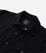 Camisa de manga larga color marrón, confeccionada en sarga de algodón, con cuello inglés, botones frontales y dos bolsillos de parche con solapa y botón en el pecho.