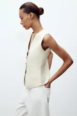 Chaleco color verde claro de punto con escote pico y cierre frontal con botones dorados.