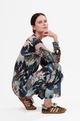 Sweater de cashmere con estampado de leopardos de las nieves en un paisaje montañoso con árboles de cerezo en flor.