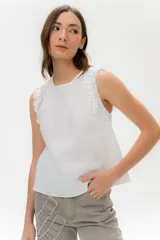 Musculosa blanca de lino con volados en los hombros, corte recto y caída liviana.