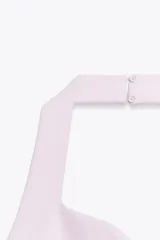 Vestido corto blanco de tejido de punto elástico, con cuello halter, escote corazón y cierre con botones en el cuello.