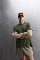 Camiseta deportiva verde militar confeccionada en tejido estructurado, ligero y elástico. Tiene cuello redondo, manga corta y bajo con aberturas laterales. Incluye logo estampado en el bajo.