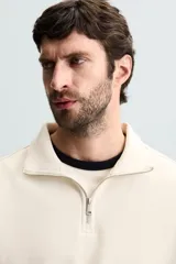 Sudadera color crema de corte recto, con cuello polo y cierre de cremallera metálica.
