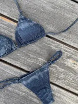 Conjunto de bikini con estampado tie-dye en tonos azul y blanco. El corpiño es de triángulos movibles con tiras para atar al cuello y espalda, y almohadillas desmontables. La bombacha es vedetina con tiritas regulables con hebilla a los costados.