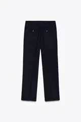 Pantalón de vestir azul marino de lana, con tiro bajo, cintura con trabillas, bolsillos laterales, raya planchada y cierre frontal con cremallera, botón y gancho metálico.