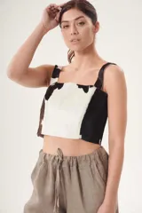 Top corto de cuero ovino con estampado de vaca en blanco y negro, de corte recto y breteles anchos.
