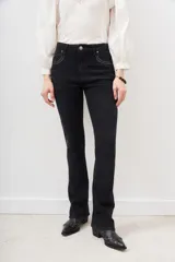 Pantalón de jean negro de corte flare con detalle de tachas metálicas en los bolsillos delanteros.