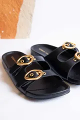 Sandalias de cuero color beige con dos tiras anchas y hebillas doradas ajustables.