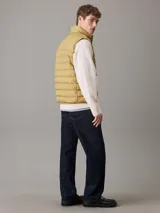 Chaleco inflable color ocre con cierre frontal y cuello alto. Tiene el logo de la marca bordado en el pecho.