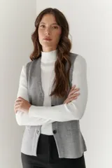 Chaleco gris de tejido de punto con cuello en V, cierre frontal con botones y bolsillos delanteros.