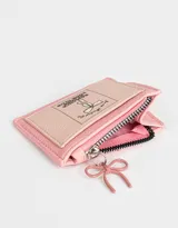 Monedero de cuerina color crudo con cierre superior, bolsillo frontal estampado con motivos japoneses y dije colgante de pagoda roja.