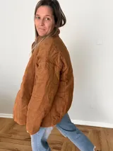 Campera color camel de corte relajado, con exterior de tejido efecto gamuza e interior acolchado. Tiene cuello alto, cierre frontal con cremallera, bolsillos laterales y bolsillo interno.