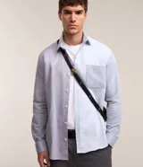 Camisa de hombre de corte clásico, confeccionada en tejido oxford con bloques de color celeste y gris. Cuenta con cuello tradicional, abotonadura frontal, mangas largas y bolsillo de parche en el pecho.