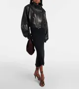 Campera bomber corta de cuero sintético negro, con cuello alto, cierre frontal, hombreras con botones a presión y bolsillos con solapa y botón a presión.