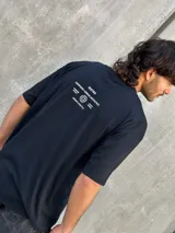 Remera negra oversize con cuello redondo y estampado pequeño en el pecho.