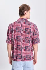Camisa de manga corta con estampado de palmeras en tonos bordó y azul.