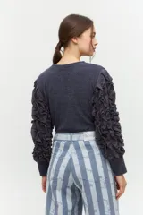 Remera negra de punto con mangas largas abullonadas con volantes.