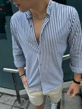 Camisa de manga larga con cuello mao y botones de madera. Diseño a rayas verticales azules y blancas.