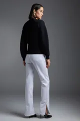 Sweater negro de punto con cuello redondo y mangas largas. Presenta tres flores tejidas en el frente y detalles de trenzas verticales.