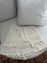 Minifalda color crudo tejida a mano en crochet, con cintura ajustable y detalle de volados en el ruedo.