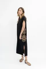 Vestido largo negro con bordado de flores color cobre en el lateral. Diseño holgado con cuello redondo y mangas cortas. Tiene aberturas laterales en el ruedo.