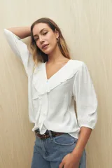 Blusa blanca con mangas 3/4 y escote en V con volados.