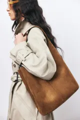 Cartera bombonera marrón de gamuza con correa ajustable y asa de hombro.