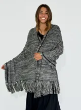 Chal de tejido de punto grueso en tonos blanco, gris y negro con flecos en el borde inferior.
