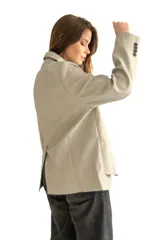 Blazer gris de silueta recta y textura sutil, con solapas de muesca, cierre con dos botones, bolsillos con solapa y puños con cuatro botones.