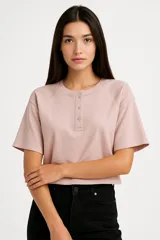 Remera cropped color rosa con cuello redondo, manga 3/4 y cierre frontal con broches.