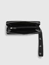Billetera Calvin Klein negra con cierre de cremallera, correa de muñeca con logo, ocho ranuras para tarjetas, dos billeteros y un bolsillo monedero con cremallera.