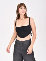 Top negro con corte irregular, breteles anchos y lazos laterales.
