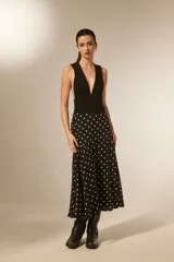 Falda larga de poliéster, color negro con estampado de lunares blancos. Corte amplio y fluido.