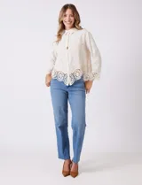 Camisa de algodón color naranja, con bordado suizo y encaje calado. Tiene cuello con solapa, botones frontales, mangas largas con terminación de encaje y ruedo asimétrico con galón de encaje.