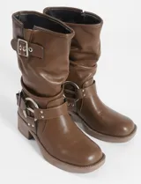 Botas marrones de caña media con hebillas plateadas y taco bajo. Fabricadas en cuero vegano.