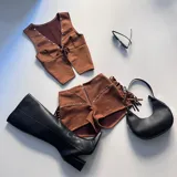 Conjunto marrón de chaleco con lazo y short con cierre, ambos con detalles de tachas.