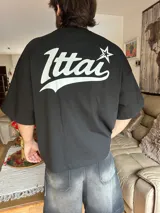 Remera negra de corte holgado con estampado en la espalda con la palabra "Ittai" en blanco y una estrella.