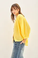 Camisa amarilla de algodón con corte amplio, cuello redondo y mangas 3/4 con puños elásticos.