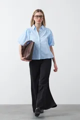 Camisa blanca de algodón con cuello camisero y mangas cortas abullonadas. Presenta un corte relajado y cierre frontal de botones.