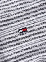 Chomba Tommy Hilfiger de corte regular, a rayas horizontales blancas y azules. Tiene cuello tipo polo gris con borde blanco, tapeta de dos botones y logo bordado en el pecho. Confeccionada en algodón orgánico y lino.