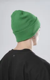 Gorro de lana verde con logo bordado en un parche negro.