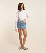 Minifalda de jean azul con bolsillos delanteros y traseros, cierre con botón y cremallera.
