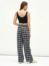 Pantalón de tela a cuadros blancos y negros, de corte recto y tiro alto con cintura elástica.