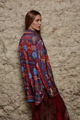 Camisa holgada estampada con motivos geométricos en tonos azul, rojo y marrón. Tiene cuello solapa, mangas largas y cierre abotonado.