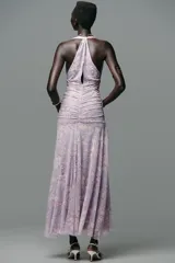Vestido largo de tul color lila con estampado de flores blancas, cuello halter con lazada y escote pico.