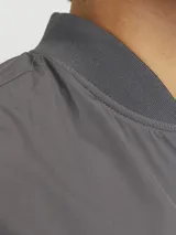 Campera bomber liviana color gris, de manga larga con cuello baseball y fit cómodo. Diseño con cierre frontal de cremallera, bolsillos delanteros funcionales y puños de canalé.
