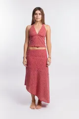 Pollera larga de tela liviana color rojo/rosado con estampado geométrico en blanco. Diseño asimétrico con corte irregular en el ruedo.