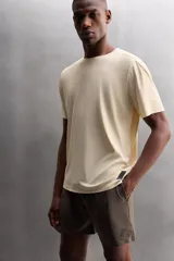 Camiseta deportiva marrón confeccionada en tejido técnico ligero y elástico con estructura perforada. Cuello redondo, manga corta y bajo asimétrico con aberturas laterales. Detalle de logo estampado.